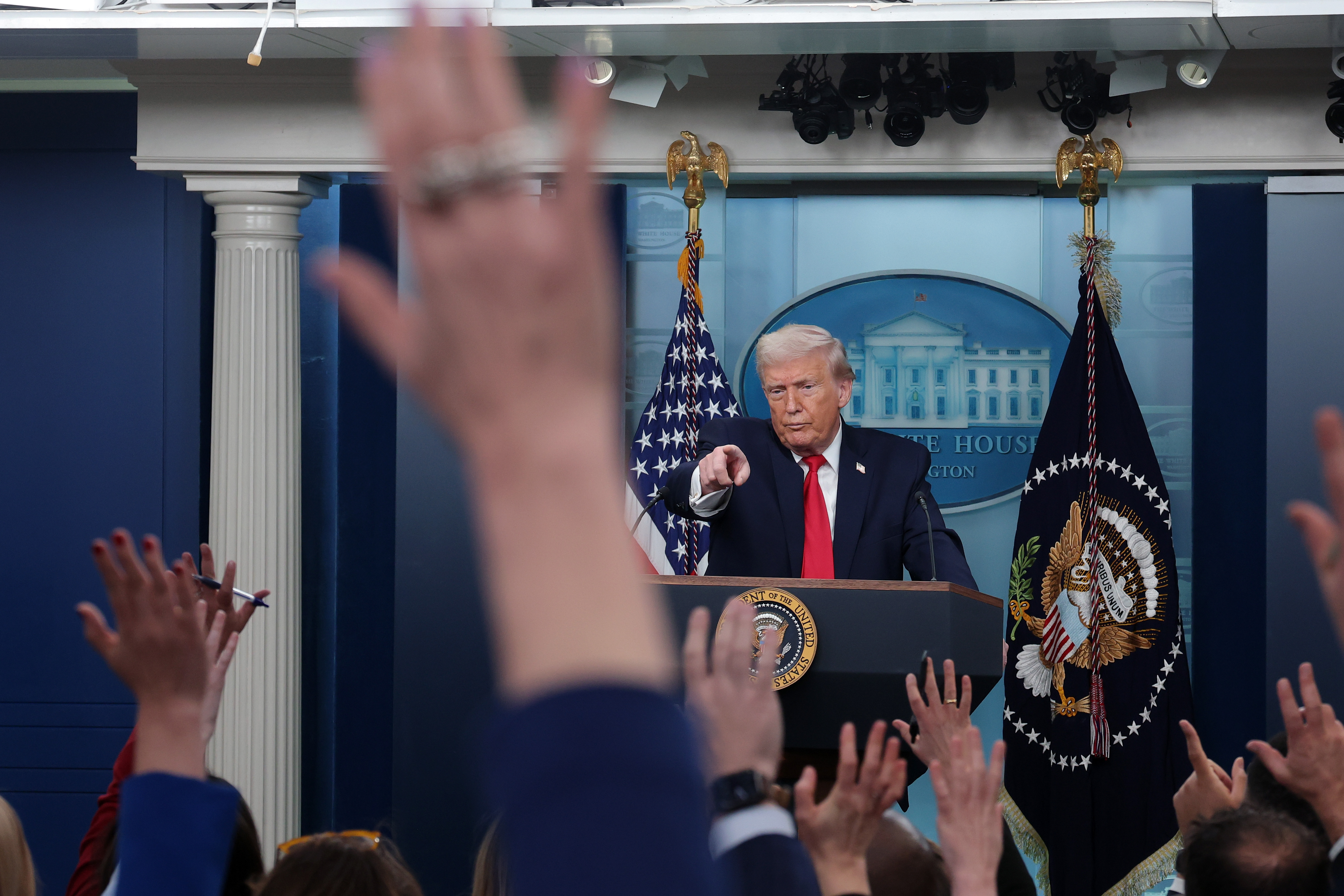 Trump points toward reporters raising their hands during a White House press briefing.