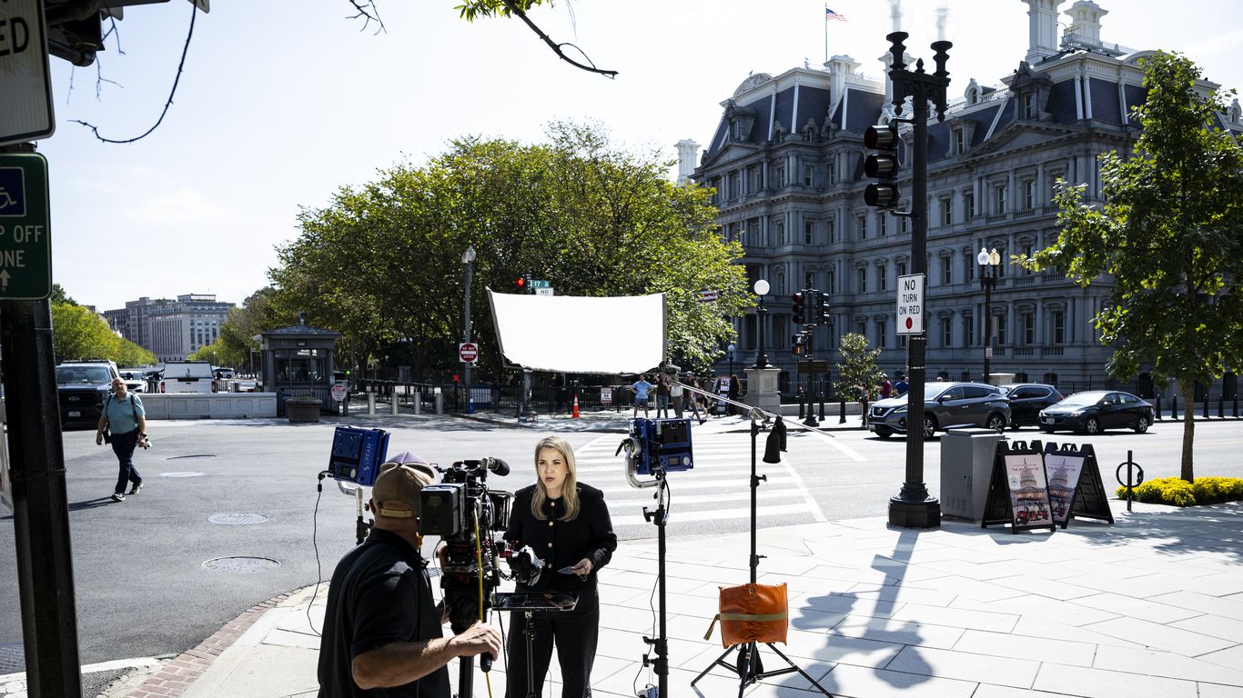 A television crew films a reporter on a sidewalk near the White House complex.